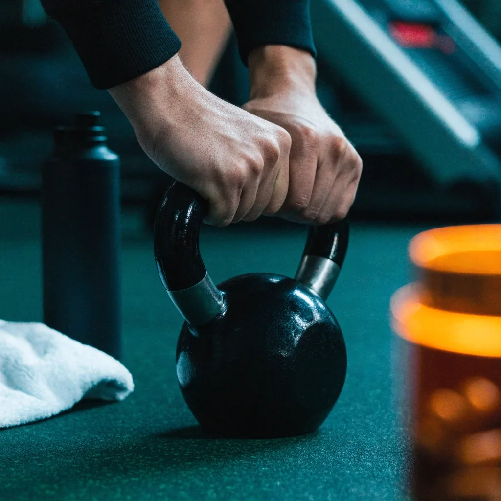 A weekly training setup on a dark emerald desk with a shaker, folded towel and an out-of-focus amber-glass bottle